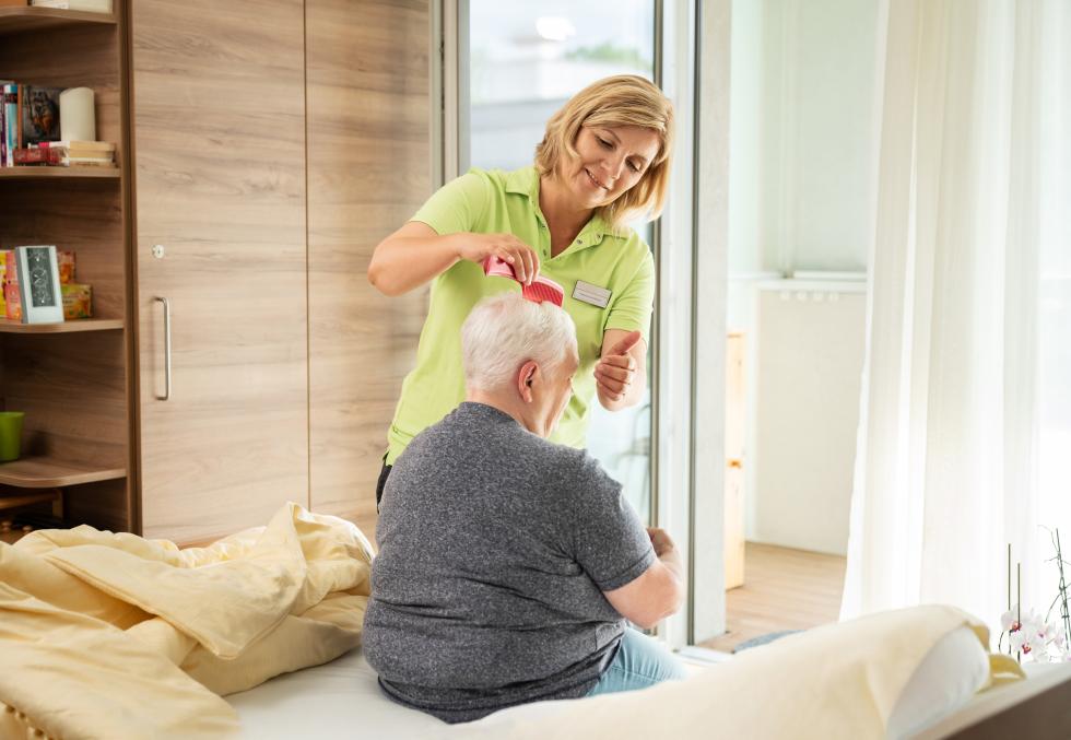 Pflegende kämmt Haare von älterer Dame